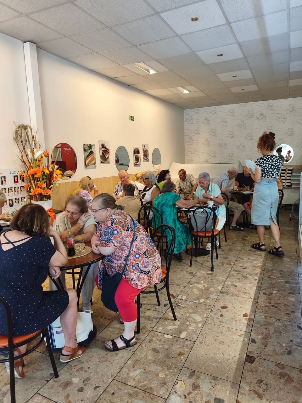 Účastníci kvízu pri stoloch v cukrárni.