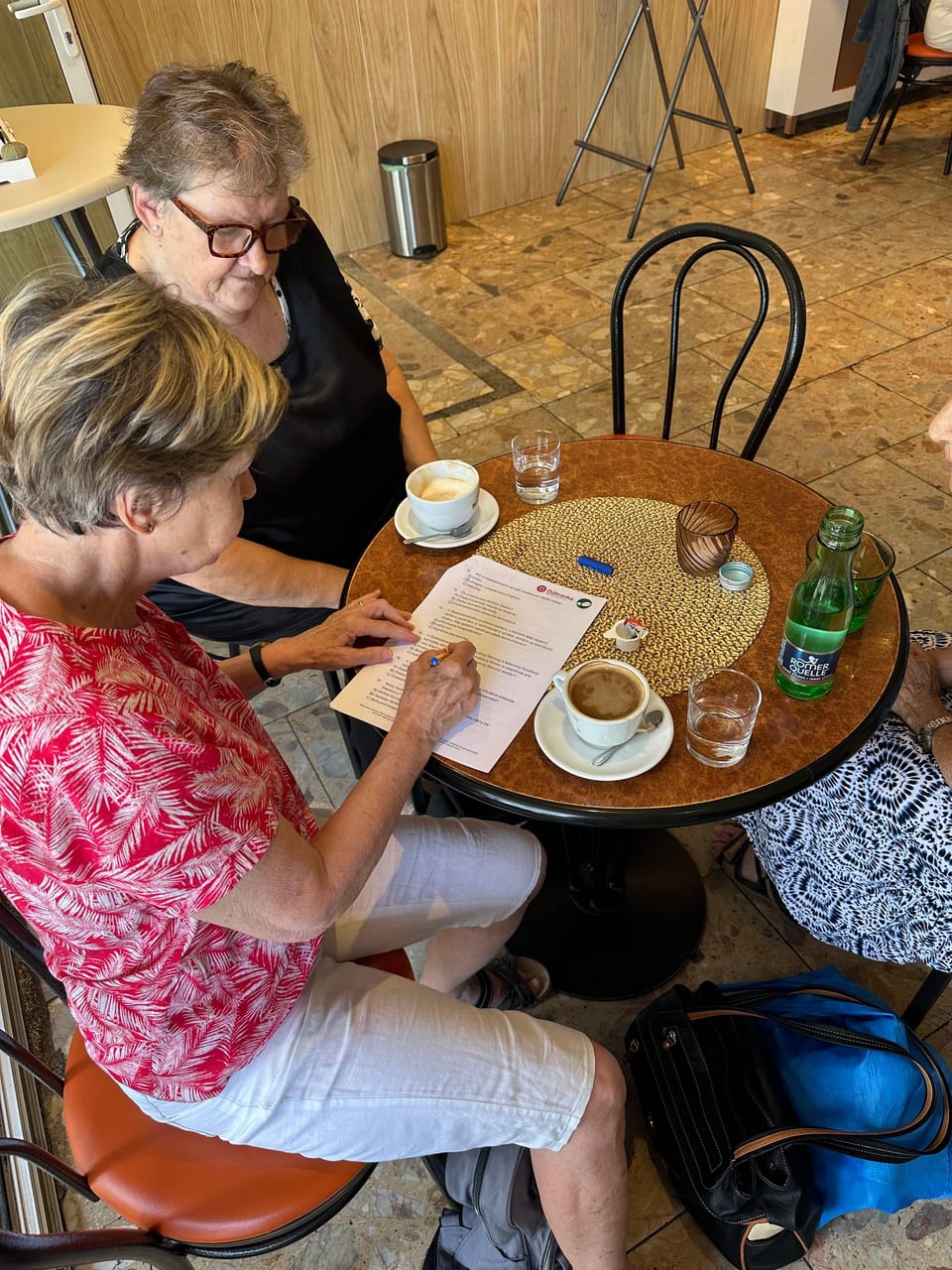 Two women filling in the answer sheet over coffee.