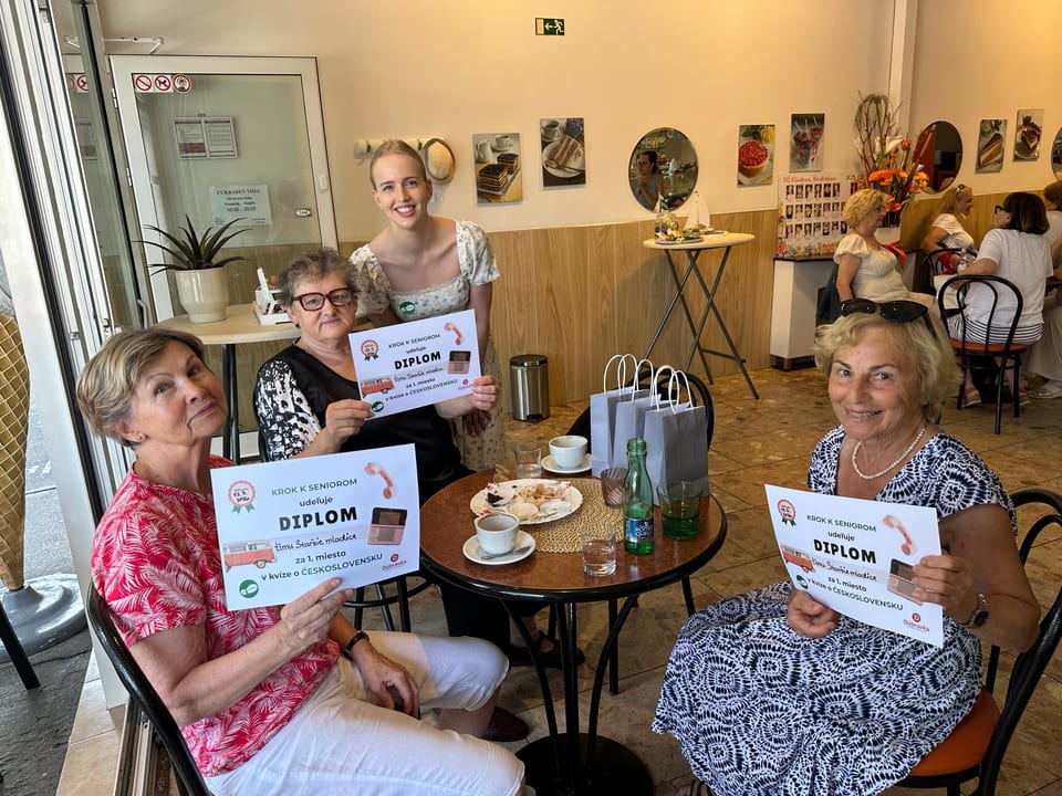 Four quiz participants holding their certificates at a table in the café.